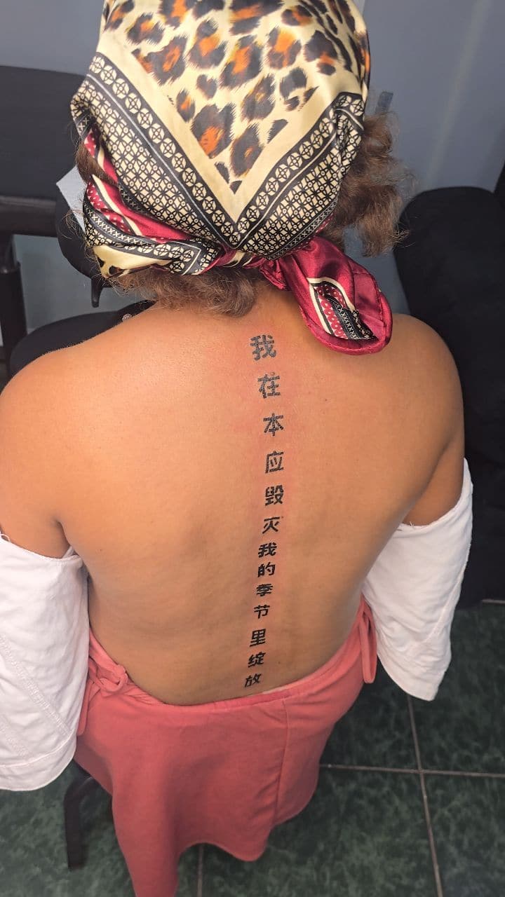 Black and grey Chinese characters tattoo on the spine, by Soulraven Studios in Kingston, Jamaica