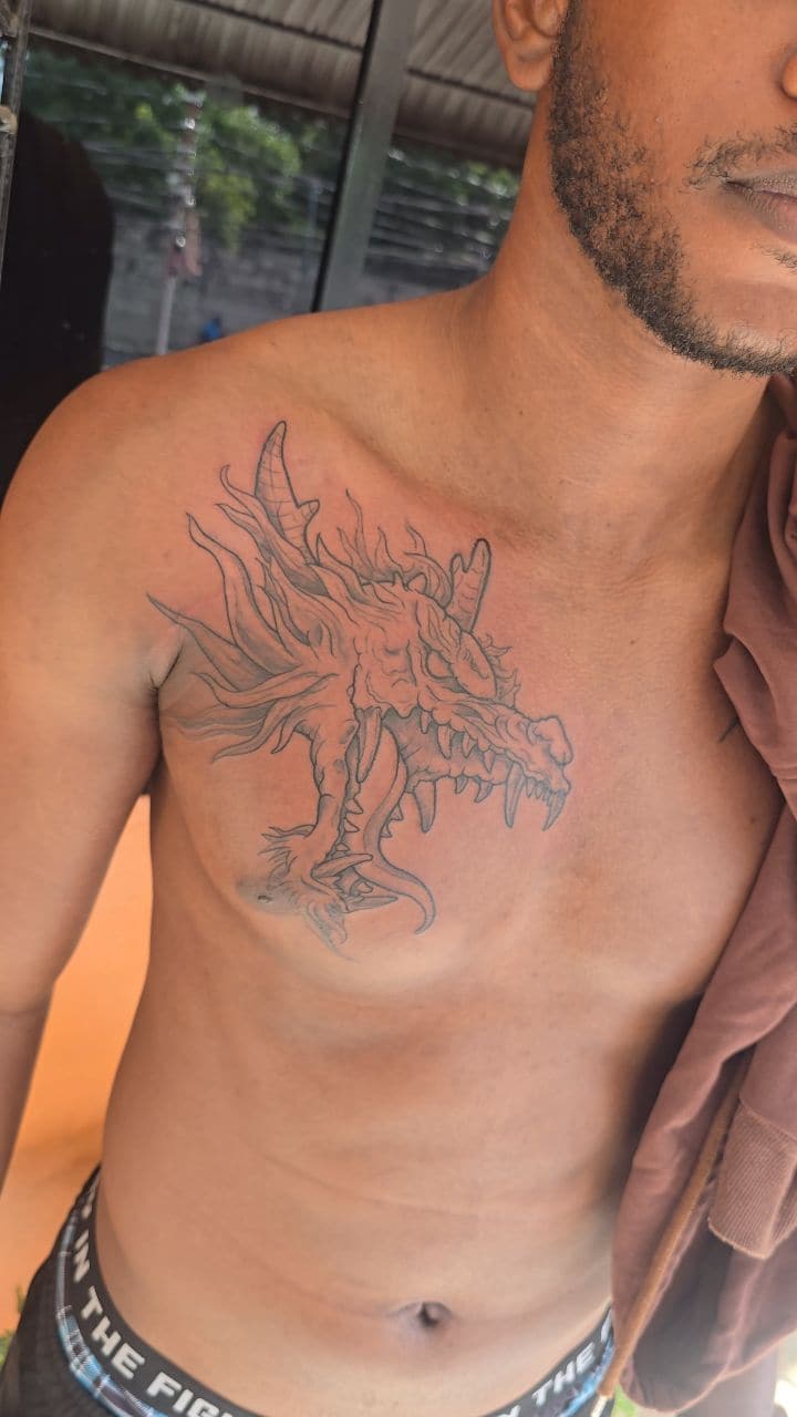 Black and grey Dragon across the chest, to be completed tattoo on the chest, by Soulraven Studios in Kingston, Jamaica