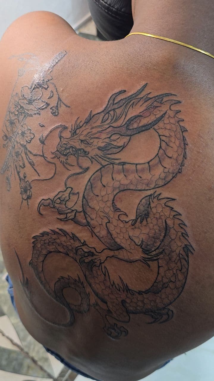 Black and grey Dragon tattoo on the thigh, by Soulraven Studios in Kingston, Jamaica