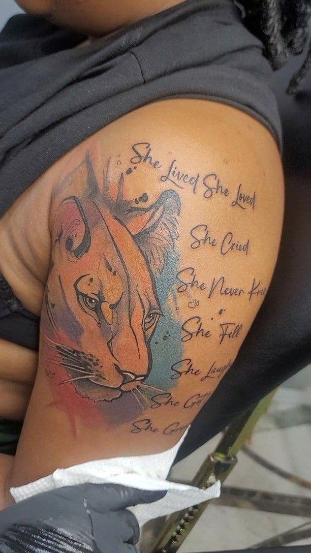 Colour Lioness with script tattoo on the thigh, by Soulraven Studios in Kingston, Jamaica