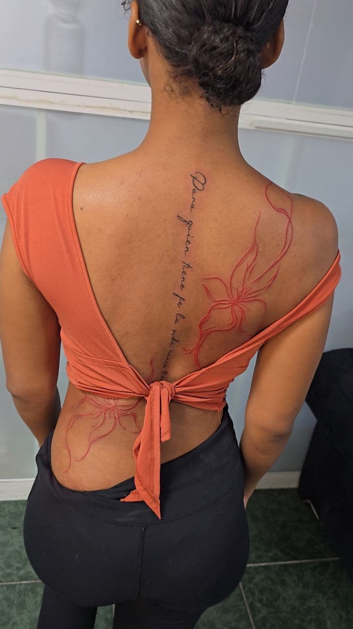 Black and grey with red Script along the spine with a red flower tattoo on the spine, by Soulraven Studios in Kingston, Jamaica