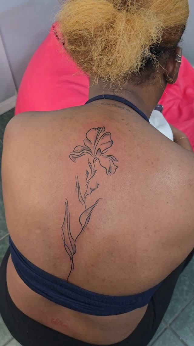 Black and grey Fine-line lily tattoo on the upper back, by Soulraven Studios in Kingston, Jamaica