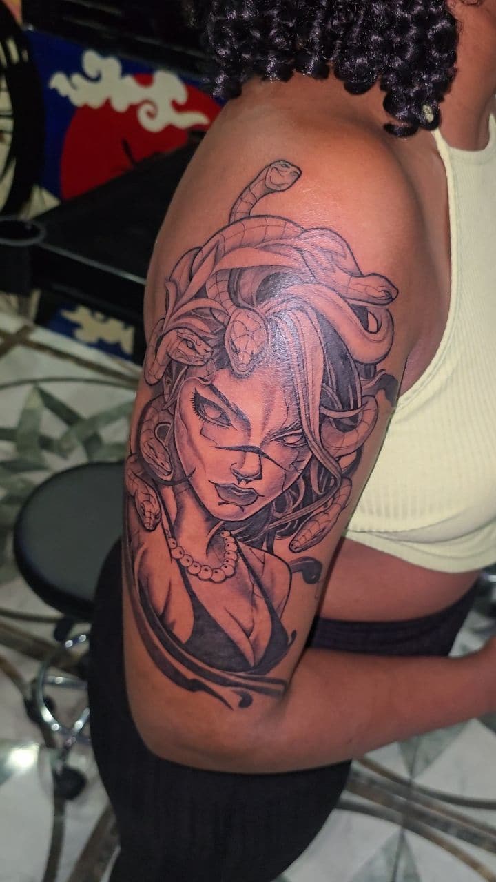 Black and grey Medusa portrait tattoo on the upper arm, by Soulraven Studios in Kingston, Jamaica