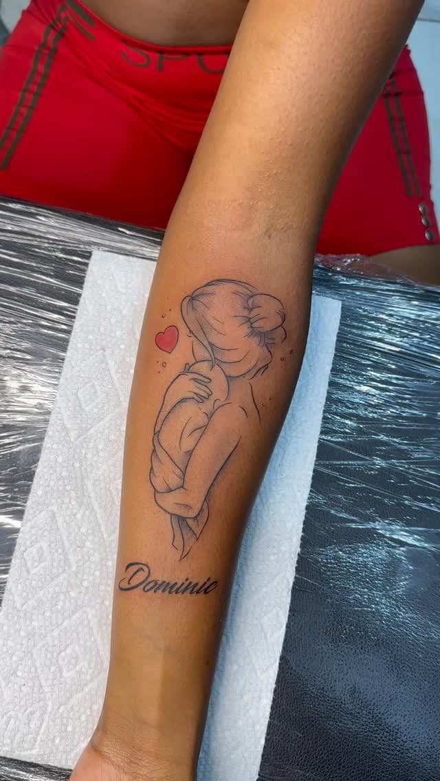 Black and grey Mother and child with a name in script tattoo on the forearm, by Soulraven Studios in Kingston, Jamaica