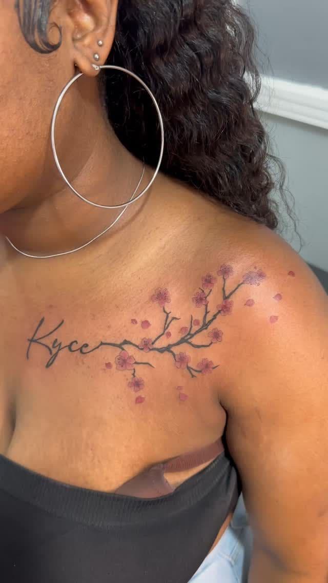 Colour Name in script with cherry blossoms tattoo on the collarbone, by Soulraven Studios in Kingston, Jamaica