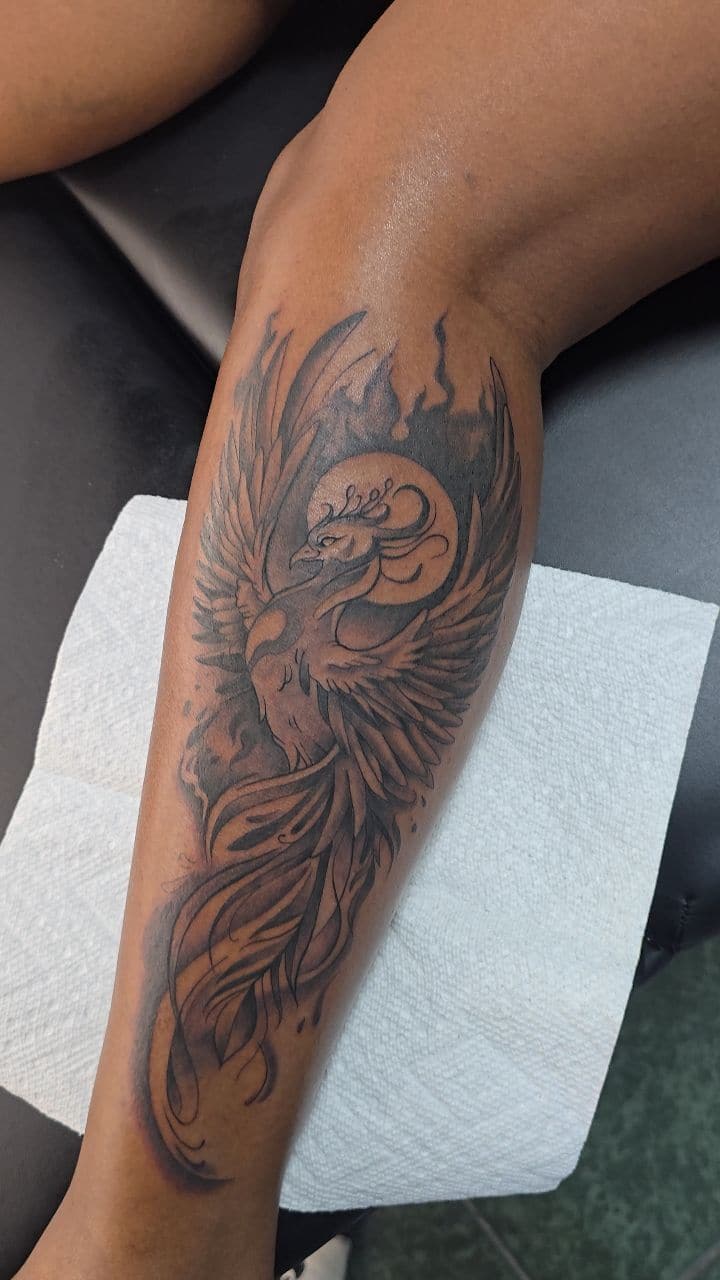 Black and grey Phoenix rising tattoo on the calf, by Soulraven Studios in Kingston, Jamaica