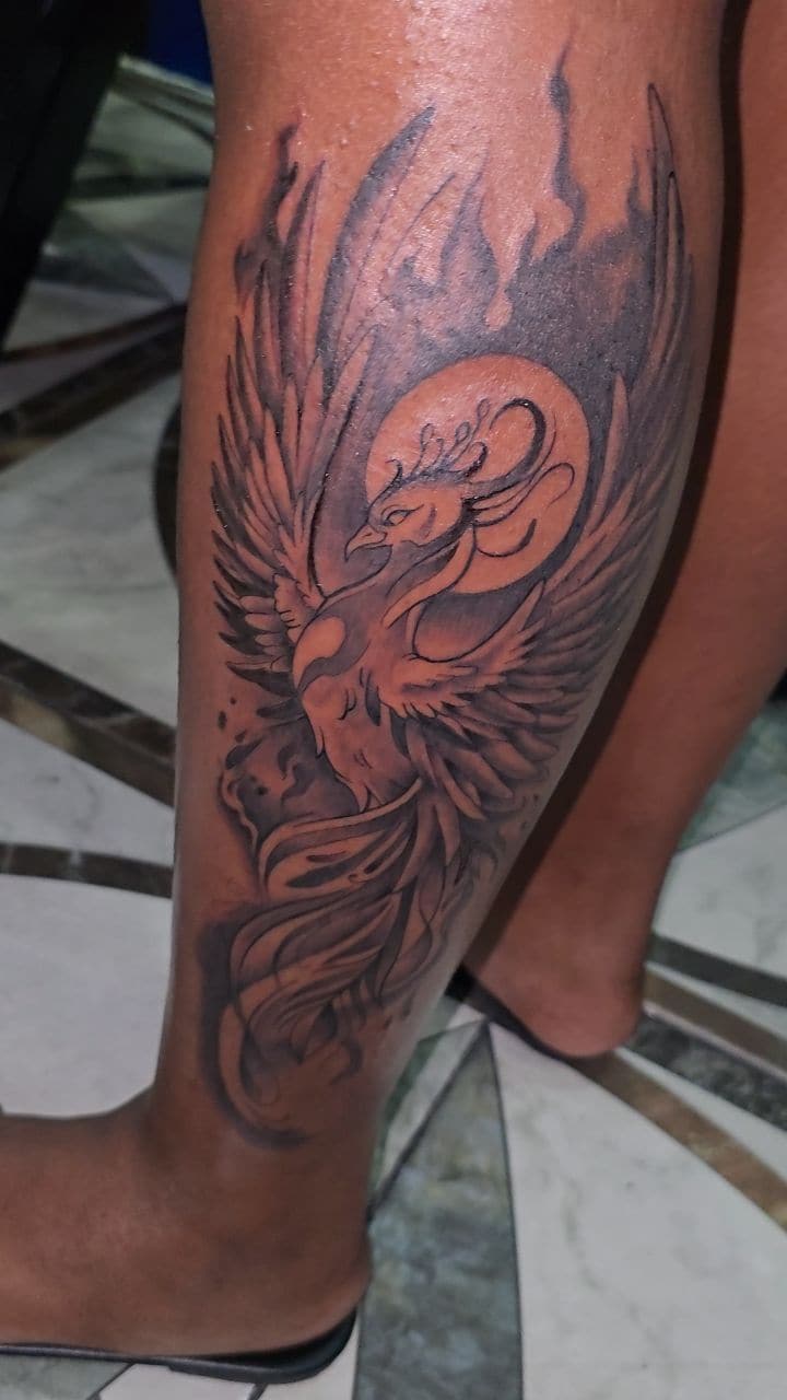 Black and grey Phoenix rising tattoo on the calf, by Soulraven Studios in Kingston, Jamaica