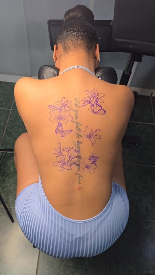 Colour Purple lilies tattoo on the spine, by Soulraven Studios in Kingston, Jamaica
