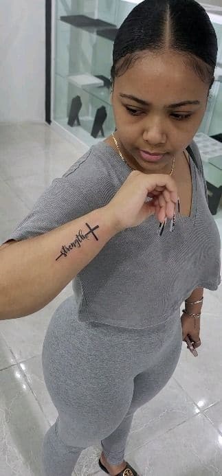 Black and grey “Strength” with a cross tattoo on the wrist, by Soulraven Studios in Kingston, Jamaica