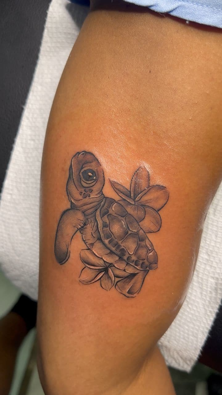 Black and grey Turtle with plumeria flowers tattoo on the leg, by Soulraven Studios in Kingston, Jamaica
